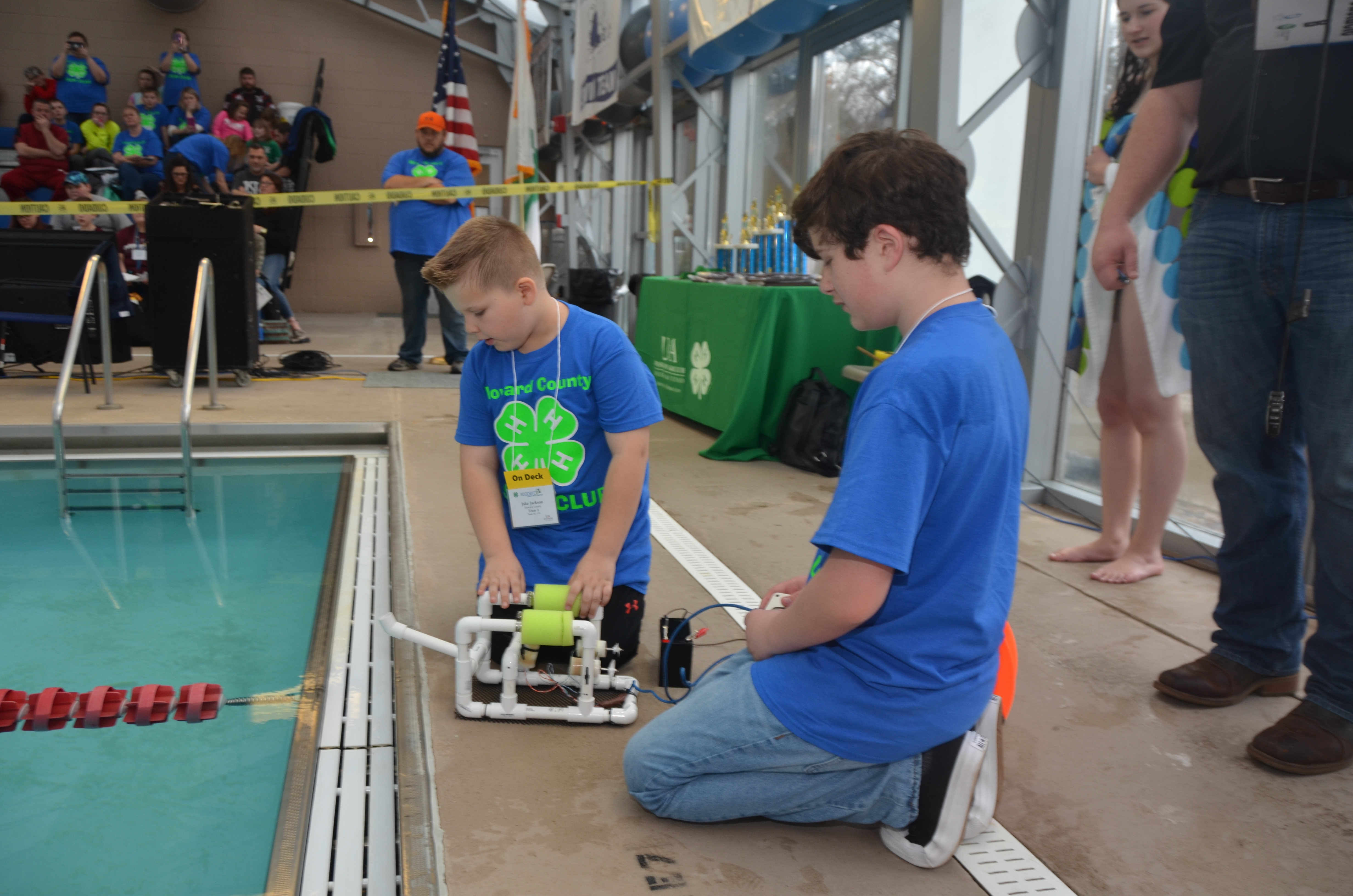 Two boys sitting at edge of pool, ready to launch their SeaPerch ROV in to the water.