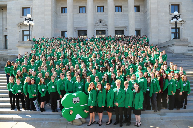 Large group of 4-H youth on the steps of the Arkansas State Capitol, all wearing green polo shirts. 