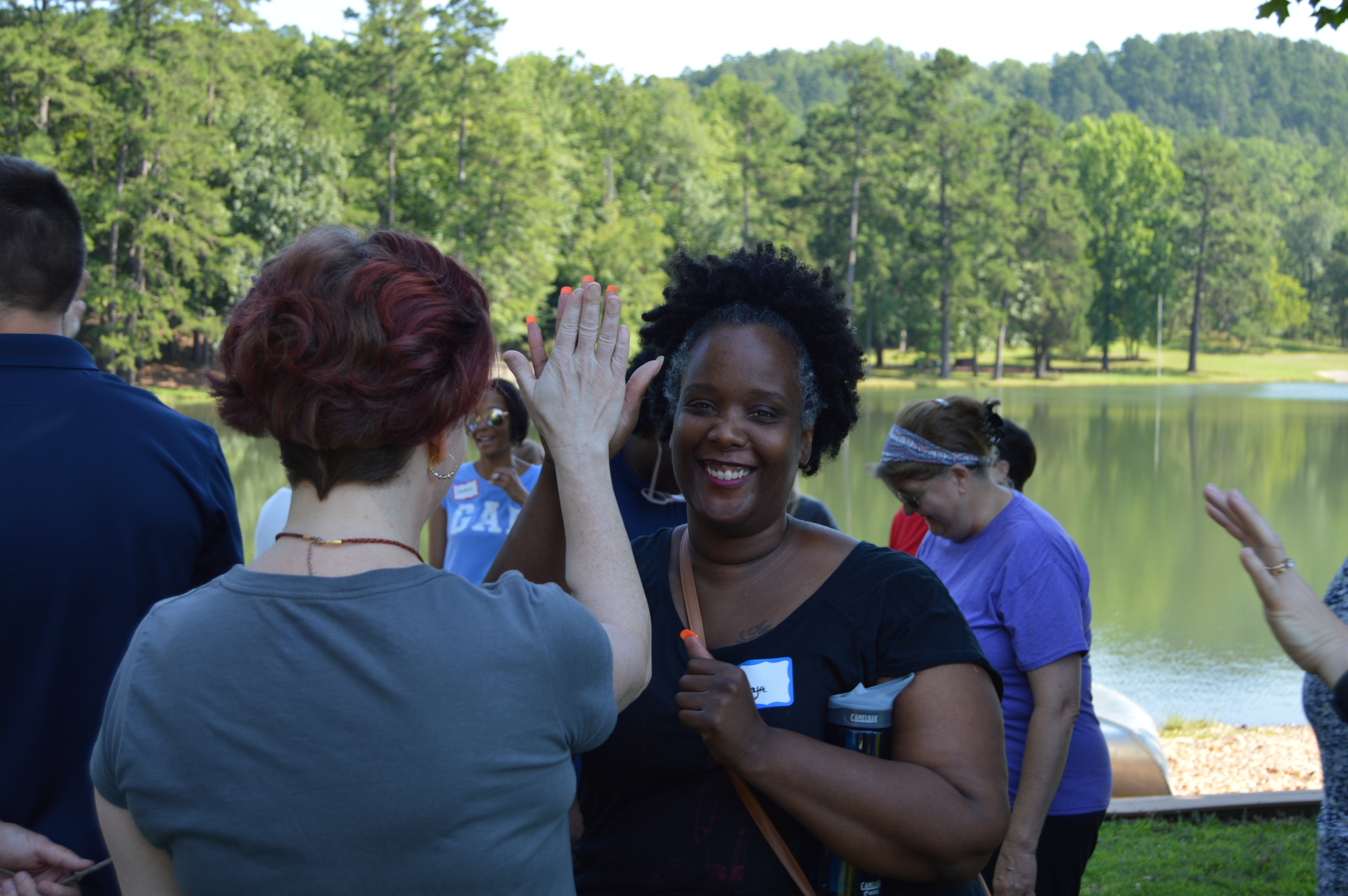 2 women outdoors high-fiving as a part of a team building activity. 