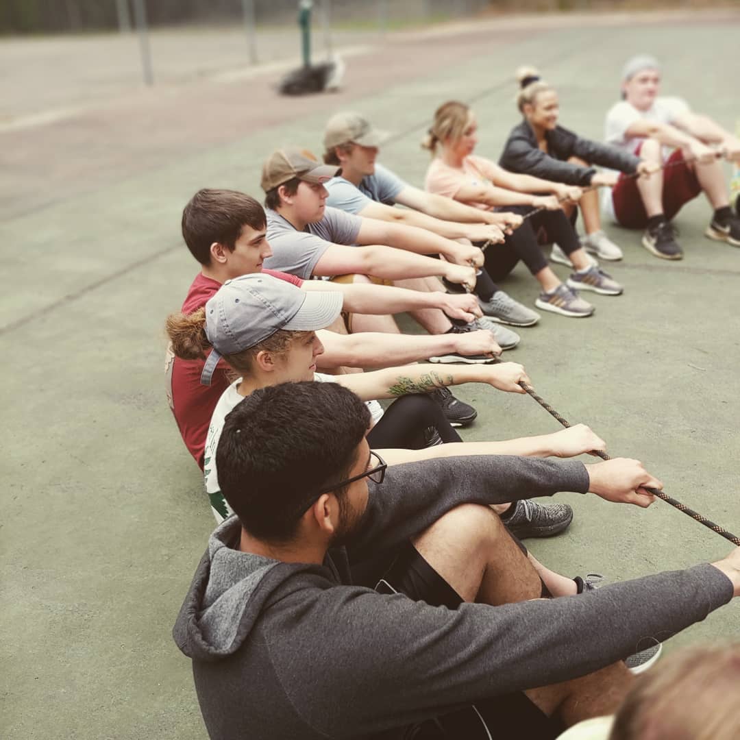 Youth in a circle, holding on to a rope as a part of a teambuilding activity.