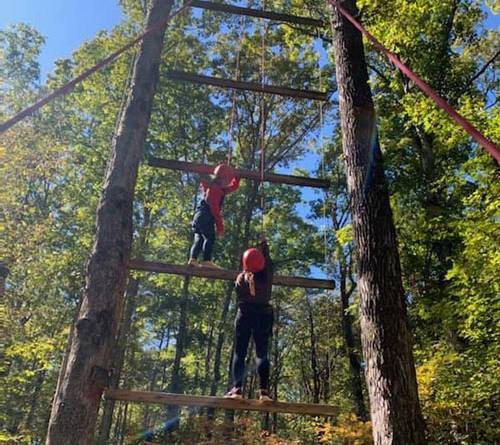 two people working together going up giants ladder